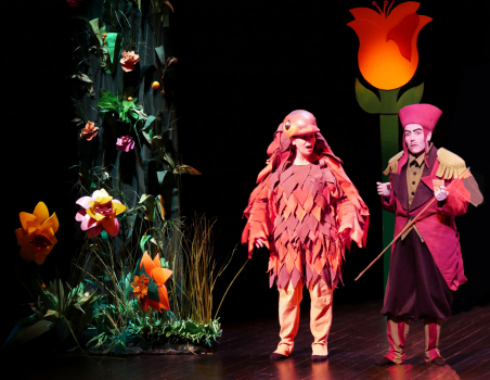 Comédiens déguisés sur scène avec un décor végétal